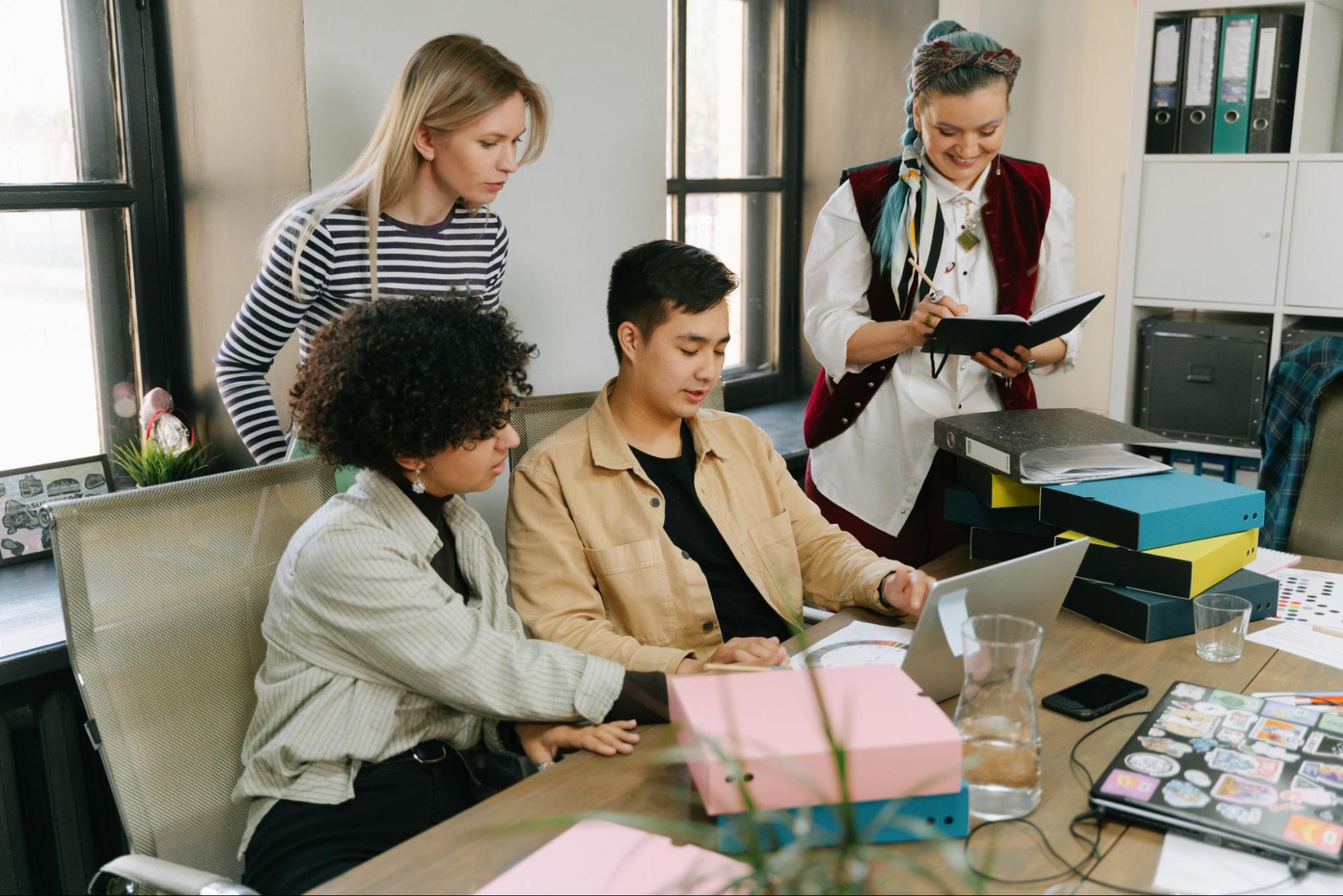 four people looking at a laptop